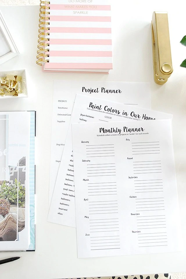 Monthly planners with a pink striped planning book on the desk.