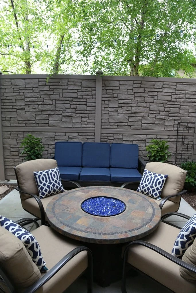 A neutral outdoor courtyard with blue cushions and blue and white pillows.