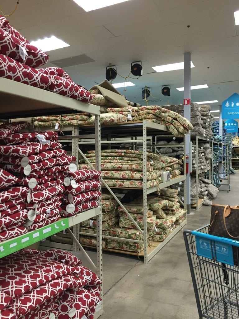 Outdoor chair cushions on metal shelves in a store.