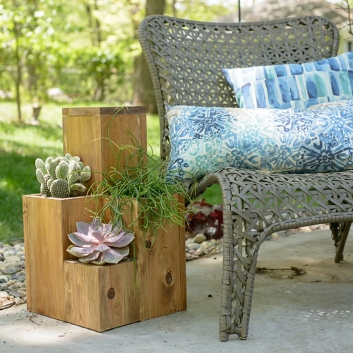 A wicker chair with pillows on it outside.