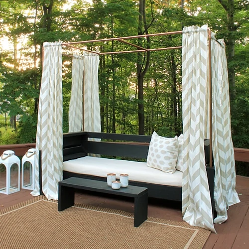 An outdoor daybed with curtains around it.