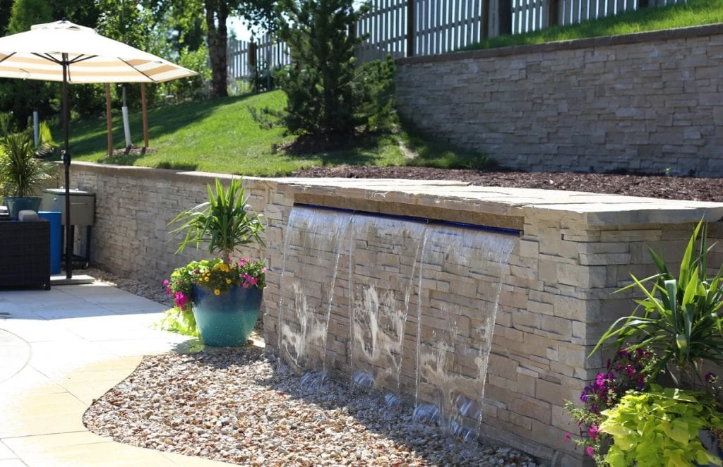Pool Water Feature with stone and brick at the side of the pool deck.