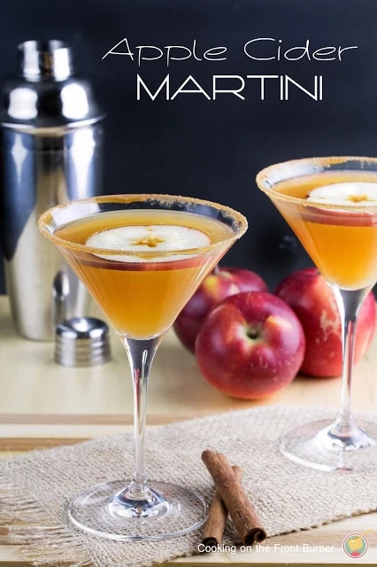 Martini glass with apple cider in it and an apple on top.