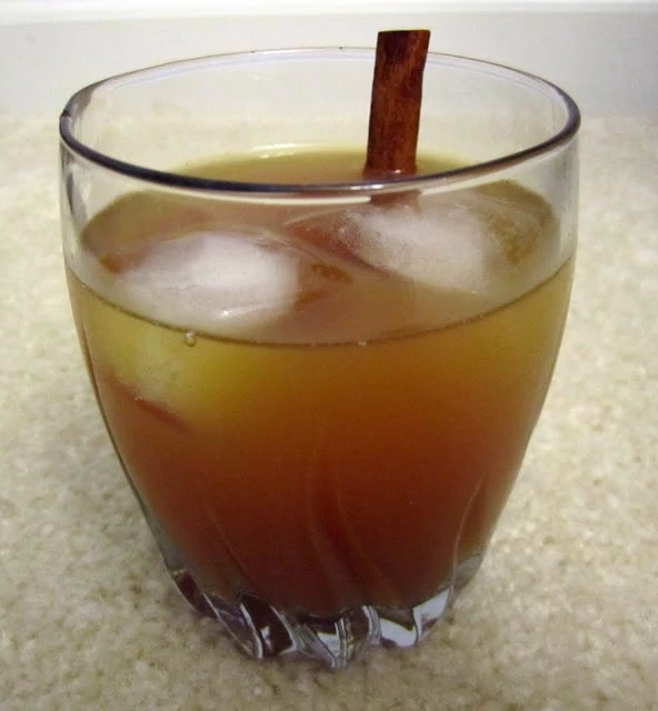 Apple cider vodka in a clear glass with ice and a cinnamon stick.