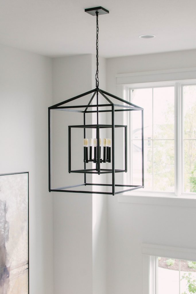 Neutral entryway with black iron chandelier. Omaha Street of Dreams design by Pearson & Company. Image via Mandy McGregor Photography.