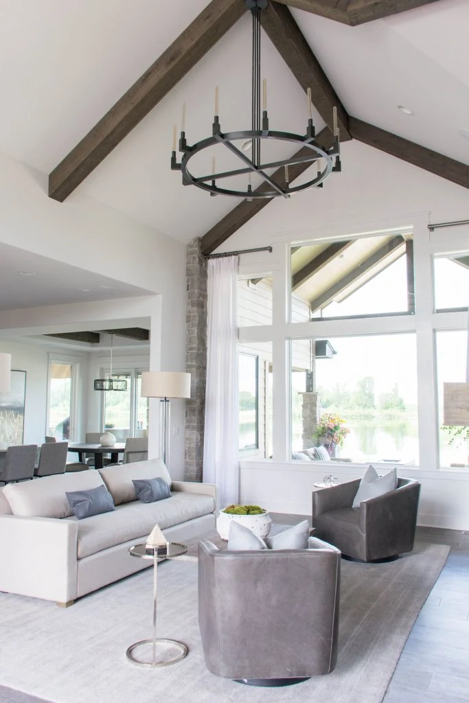 Neutral living room with vaulted ceilings, wood beams, white walls and blue and gray accents. Omaha Street of Dreams design by Pearson & Company. Image via Mandy McGregor Photography.