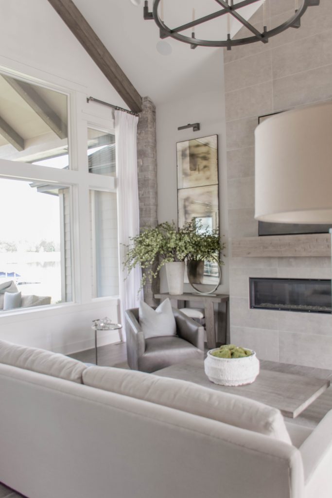 Neutral great room with vaulted ceilings, wood beams, white walls and blue and gray accents. Omaha Street of Dreams. Image via Mandy McGregor Photography.