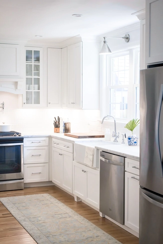 White kitchen with light wood floors and silver accents