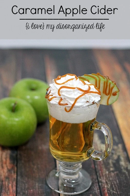 Apple cider in a glass mug with whip cream and caramel sauce on top.