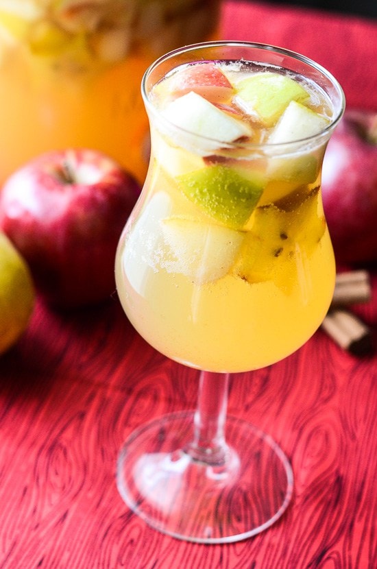 Sangria in a wine glass with apple slices in it.