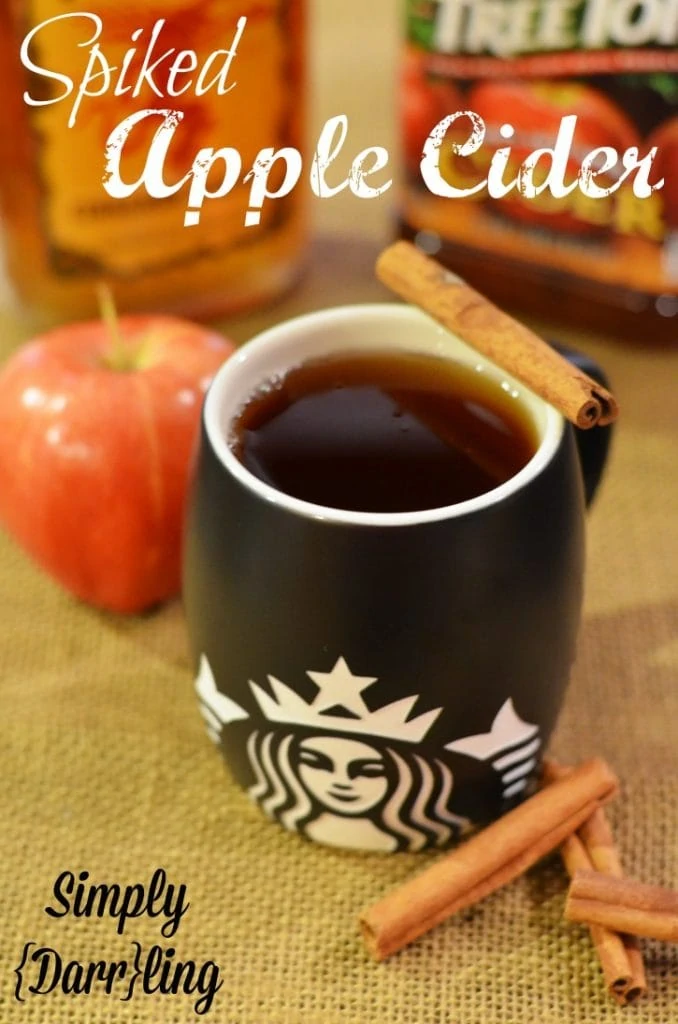 Spiked apple cider in a Starbucks mug and cinnamon sticks beside it.