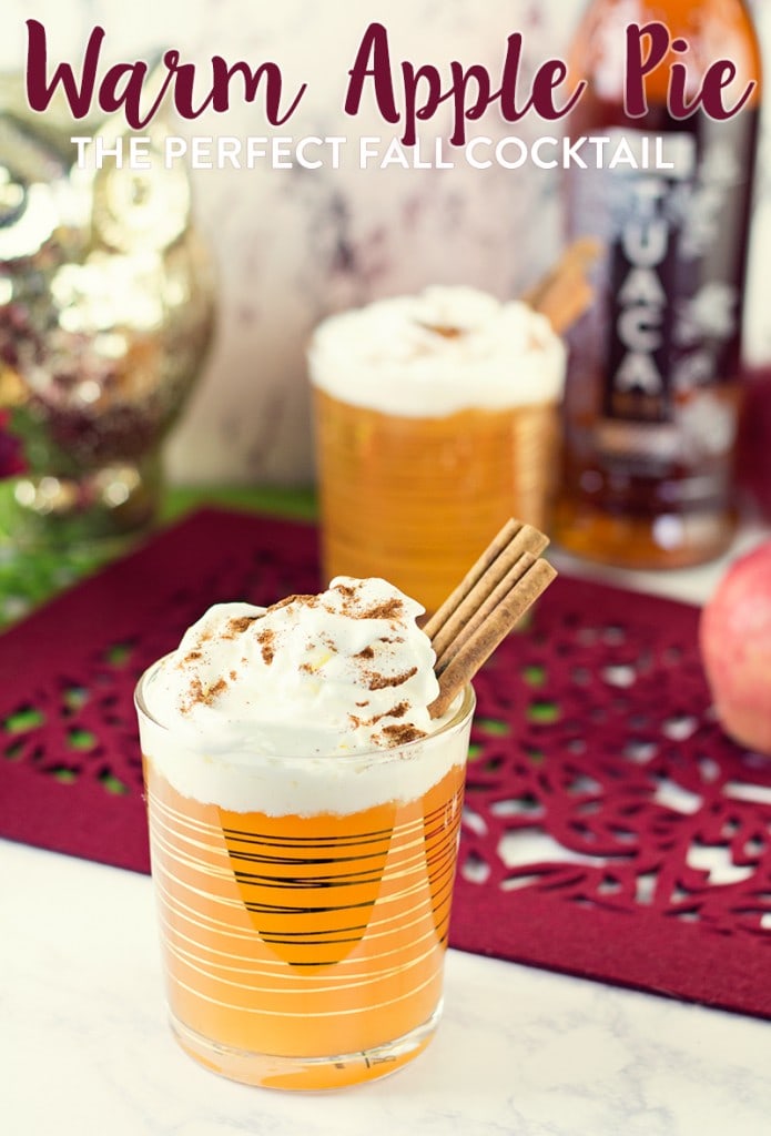 Apple pie cocktail in a glass with cinnamon sticks and whip cream on top.