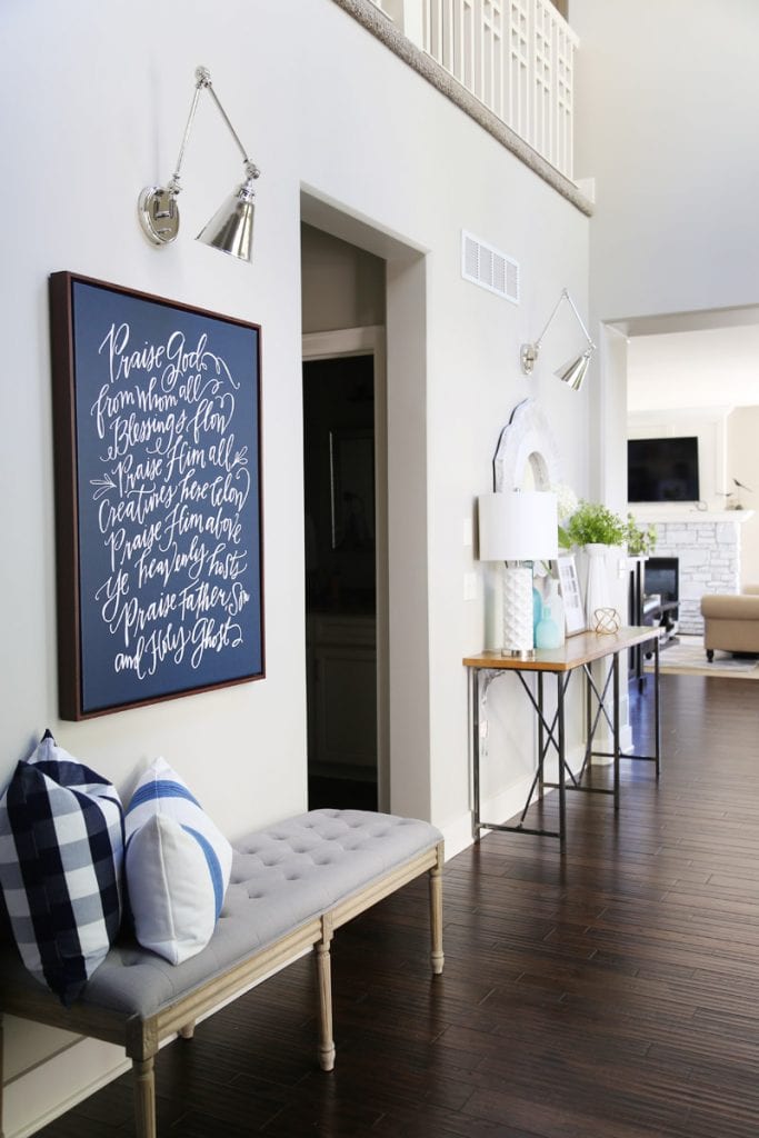 Blue and white canvas in the foyer with a gray fabric bench and pillows.