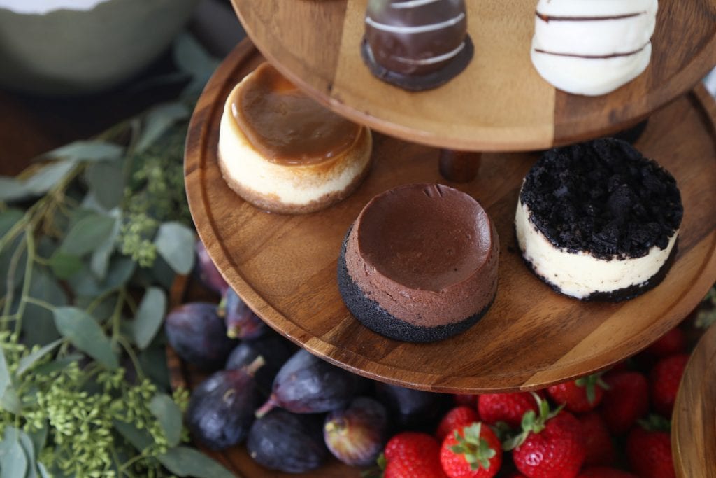 Wooden tray with three levels filled with delicate pastries and fruit.