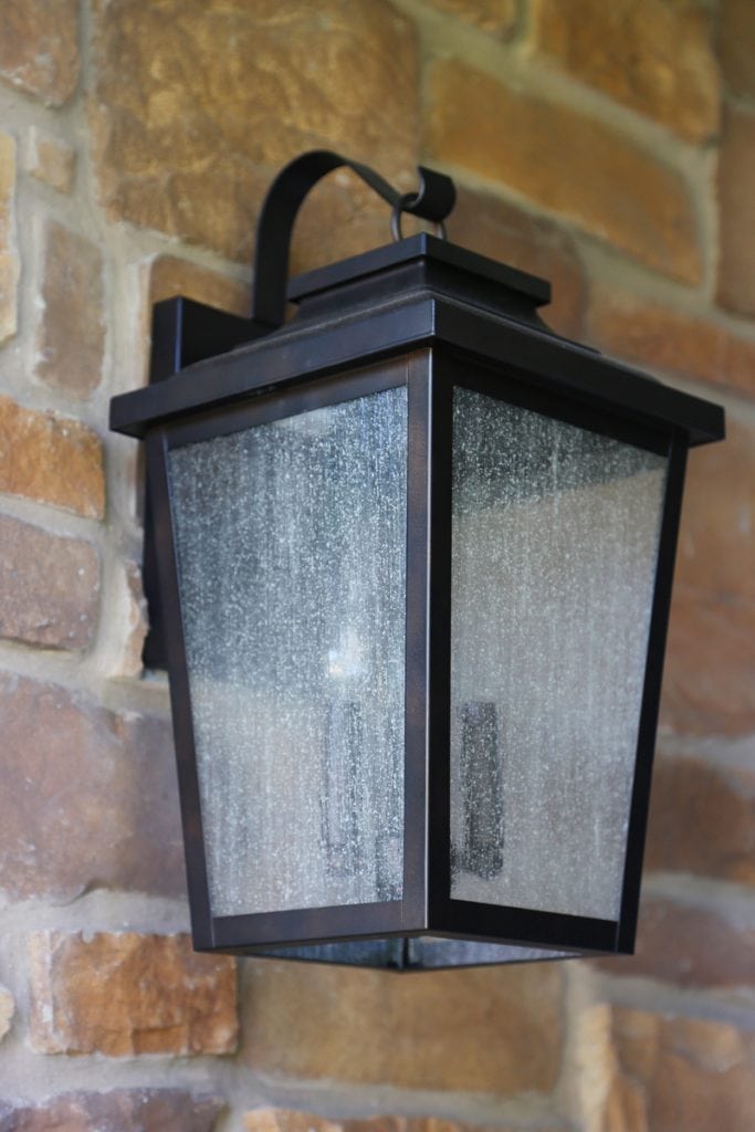 The new porch light is installed on the brick siding of the house.