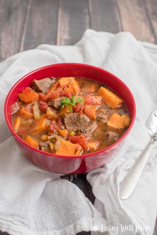 Beef stew in a red bowl with white napkins.