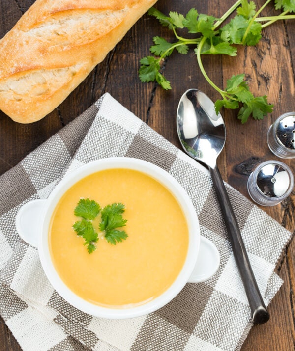 Butternut squash soup in a white bowl on a checkered napkin. 