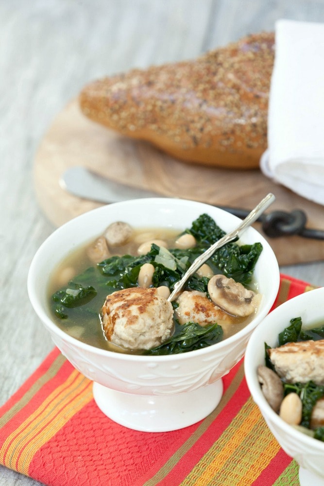 Italian meatball soup in a bowl with bread beside it.