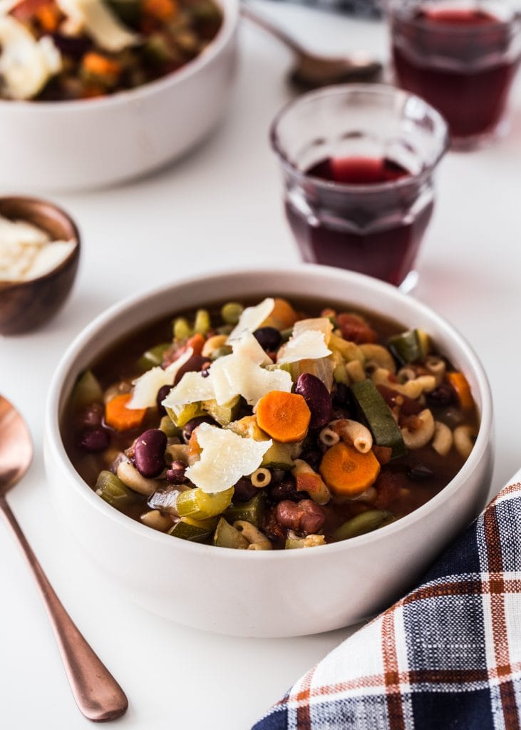 Minestrone soup on a white table with a plaid napkin.