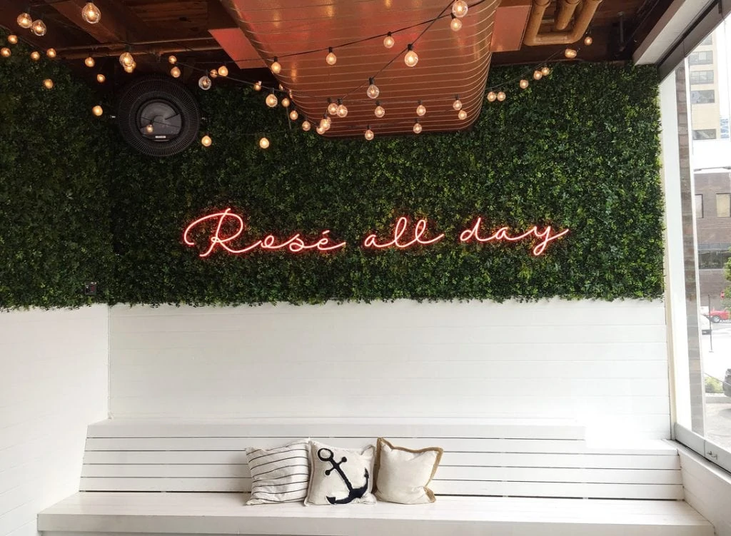 A Rose All Day sign above a bench in the restaurant.