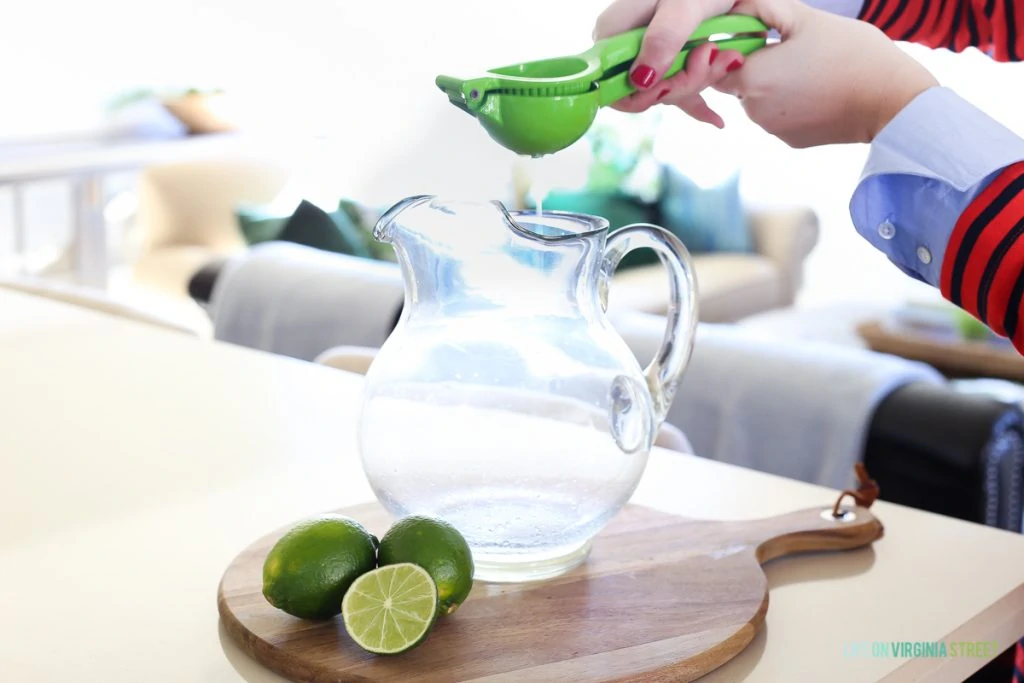 Squeezing lime juice into a clear pitcher.