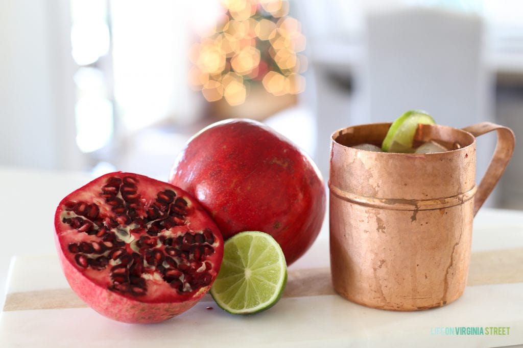 A copper mug and half a pomegranate with a lime beside it on the counter.