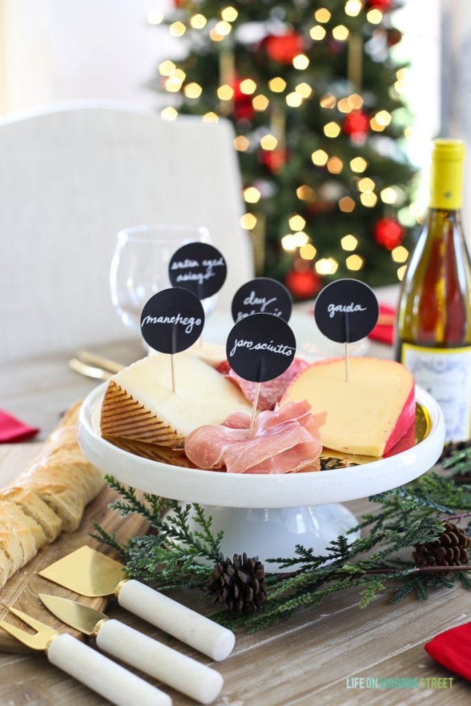 A selection of white cheeses on a platter with a bottle of white wine beside it.