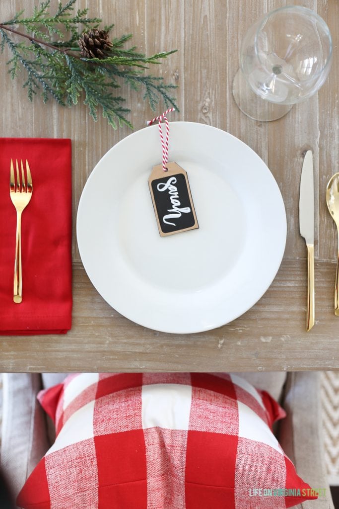 A white plate, red napkin and a tree branch on the decorated table.