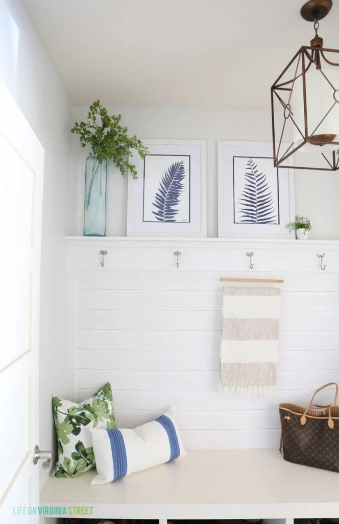 Blue and white mudroom with shiplap walls, striped throw, fig leaf pillows and blue palm artwork!