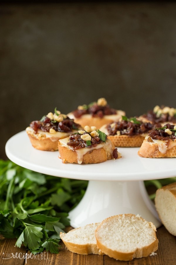 Cranberry bacon crostini's on a white cake stand.