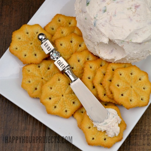 Ham and onion ball on a plate with crackers and a silver spreader.