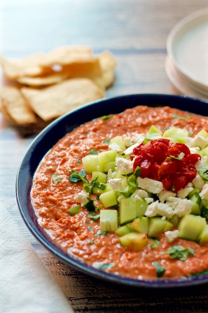 A bowl of hummus on the table with crackers.