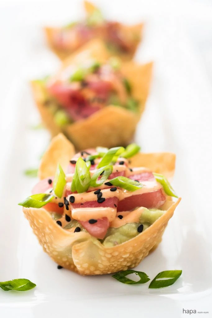 Tuna sashimi in little pastry shells on a white plate.