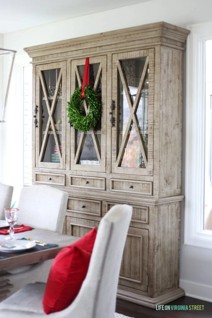 Christmas dining room with boxwood wreath and red ribbon on driftwood hutch.