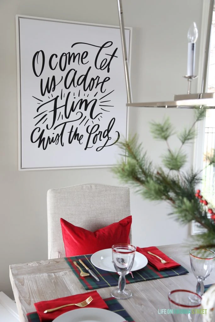 Christmas dining room with navy and red plaid and 'O Come Let Us Adore Him' canvas art.