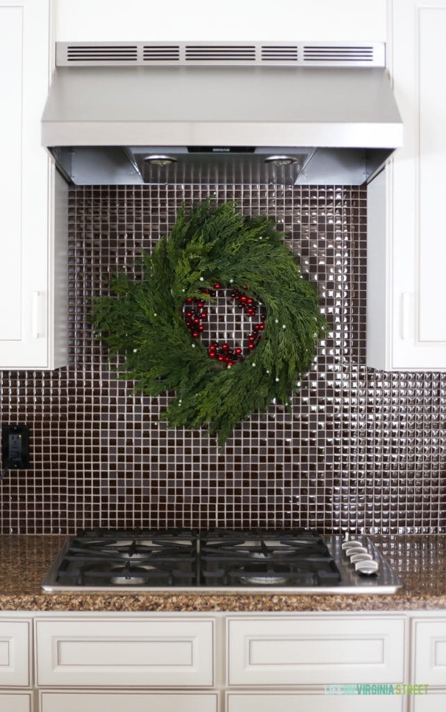 Faux cedar wreath hanging over stove on backsplash in a Christmas kitchen.