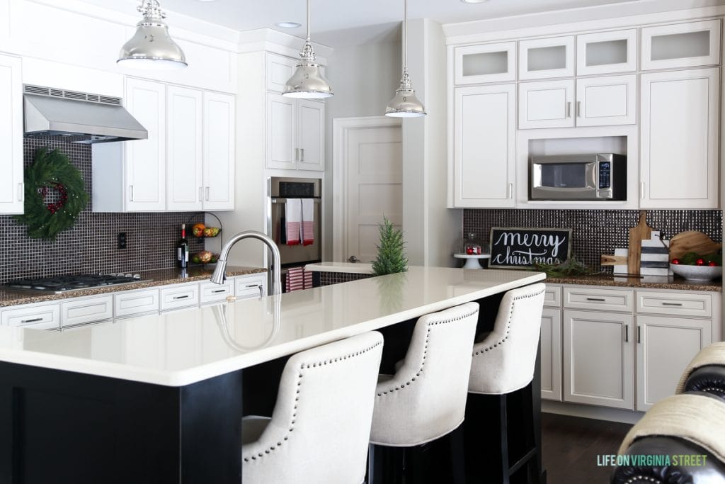 Christmas decorated kitchen with evergreen accents, wood Merry Christmas Sign and red and green accents.