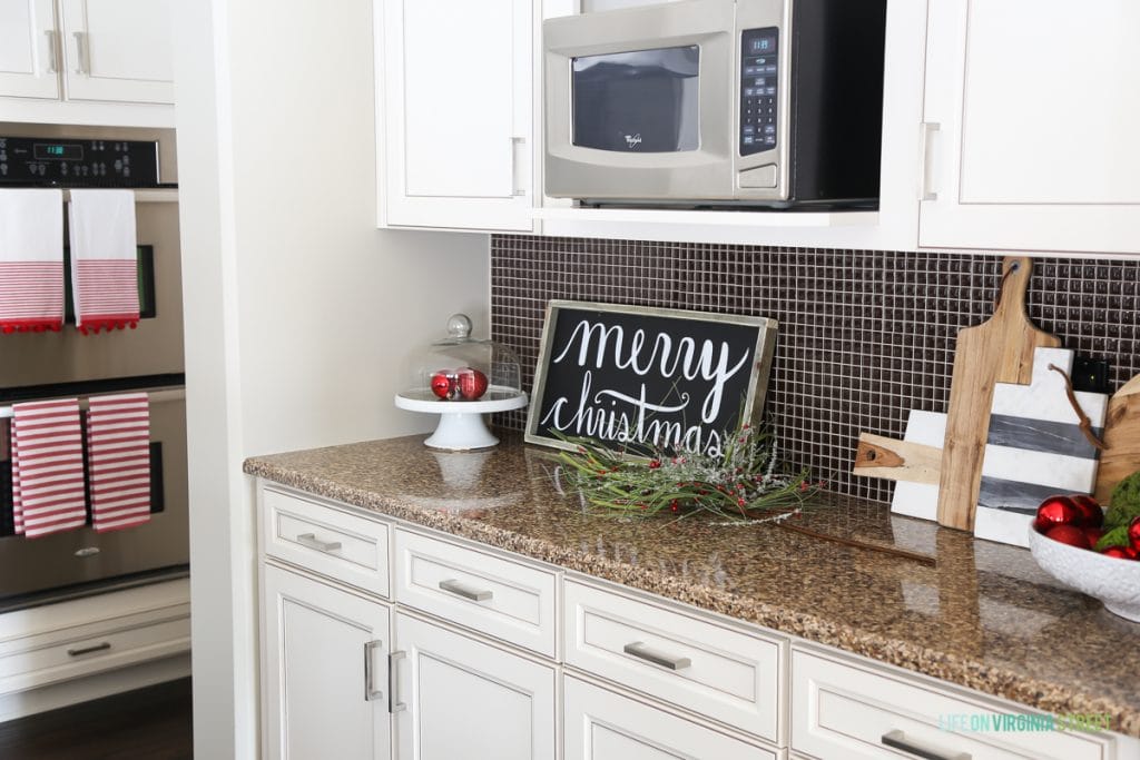 Christmas kitchen with Merry Christmas sign, holiday towels on the oven and red and green accents.