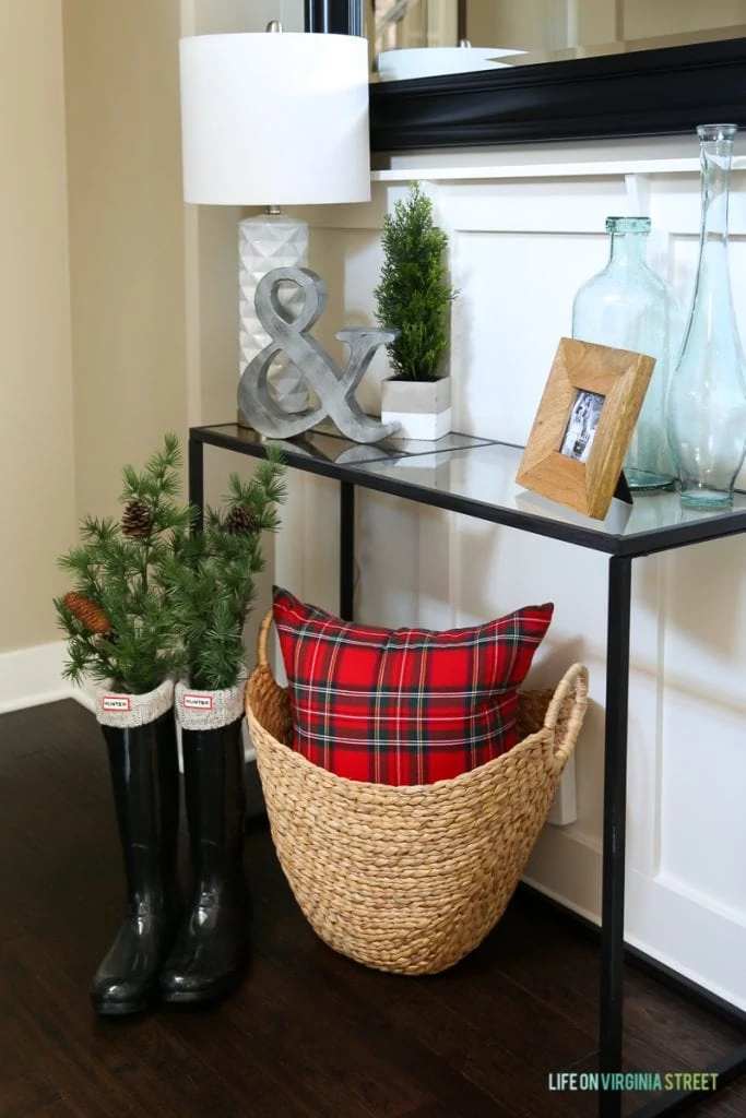 Entryway Christmas vignette with red plaid, basket and Hunter boots.