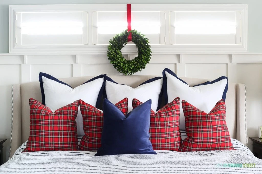 Christmas bedroom with red plaid pillows and navy and white accents.