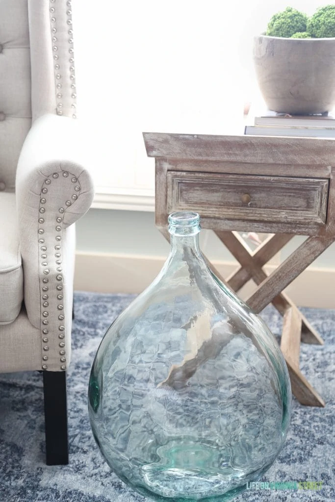 Large clear glass vase in front of side table.