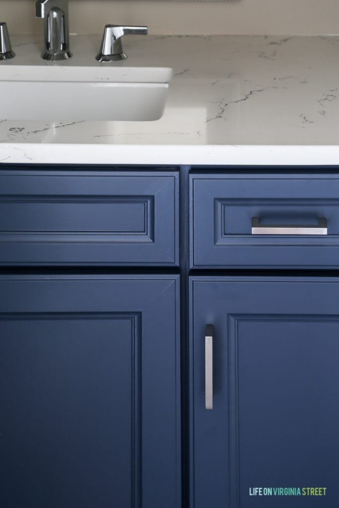 Powder bathroom cabinets freshly painted in a cool navy blue, Delta Faucet faucet, Behr Castle Path Walls and Benjamin Moore Hale Navy Cabinets. Love the fresh, nautical vibe! Countertops are Daltile One Quartz in the Luminesce color.