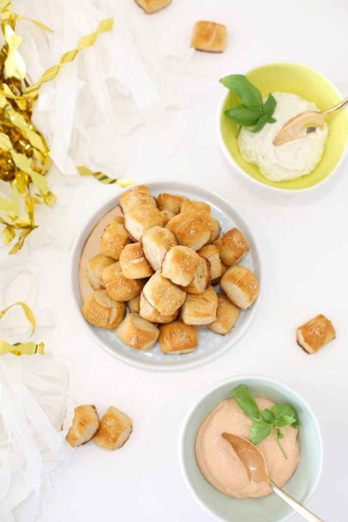 A bowl of little pretzel bites with sauces beside it.