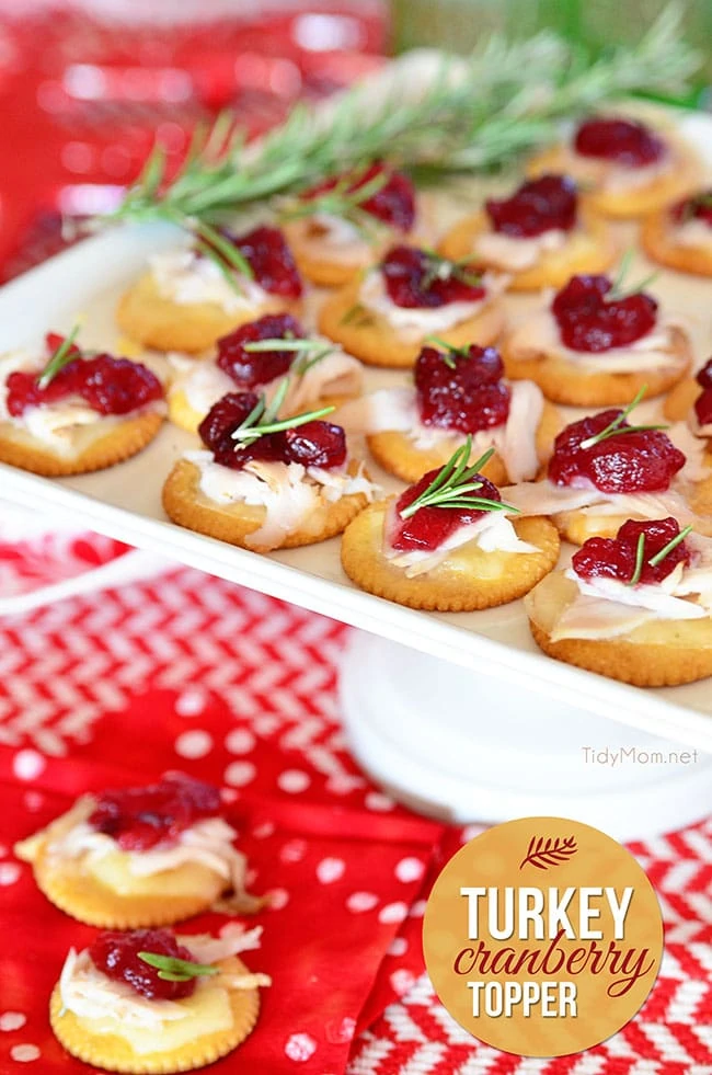 Crackers with turkey and cranberry on a white tray.
