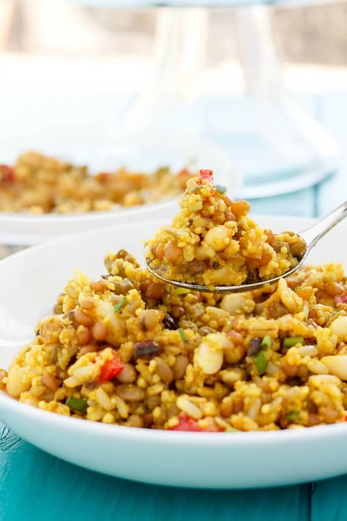 Seven grain salad in a white bowl on the table with a spoon taking a scoop.