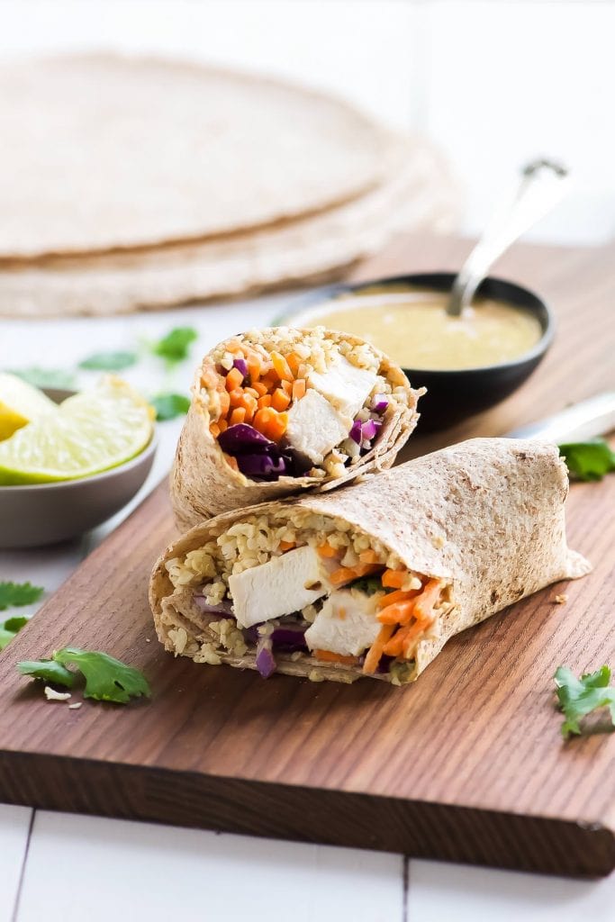  Thai style peanut chicken wraps on a wooden cutting board.