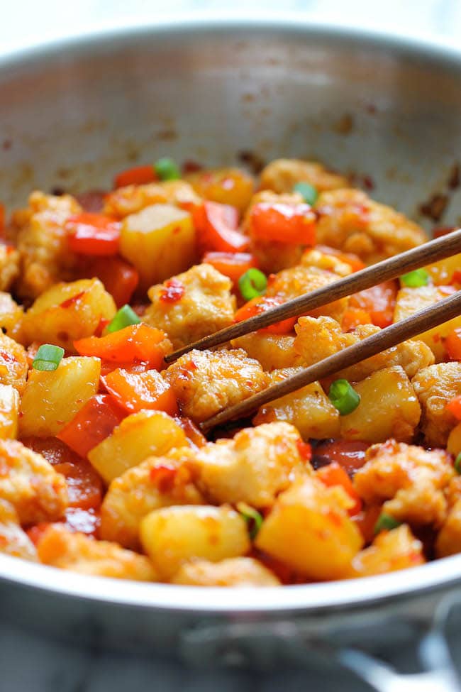 Sweet fire chicken in a bowl with chopsticks about to pick up a piece.