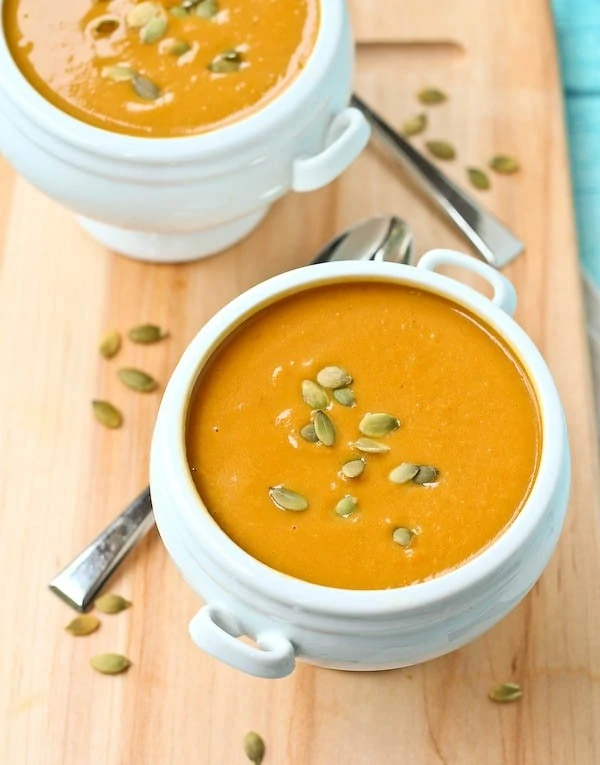 Butternut squash soup in two bowls with pumpkin seeds on top.