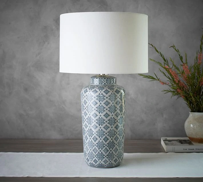 A blue and white patterned lamp on a white table runner.