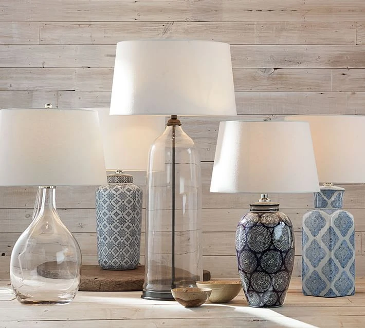 Blue and white plus clear glass lamps on a wooden table displayed.